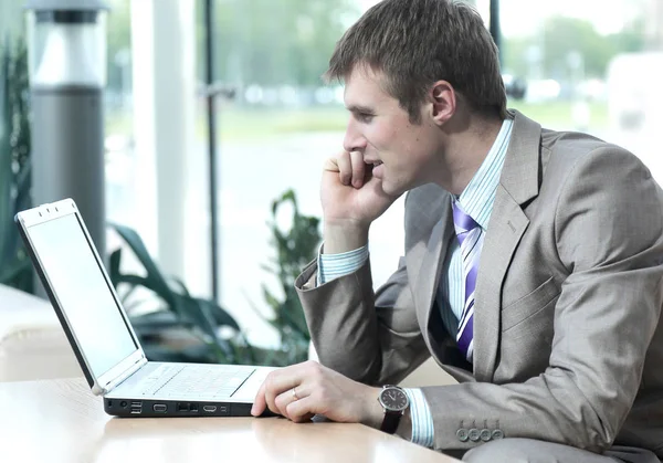 Attractive european guy talking on phone while using laptop. — Stock Photo, Image