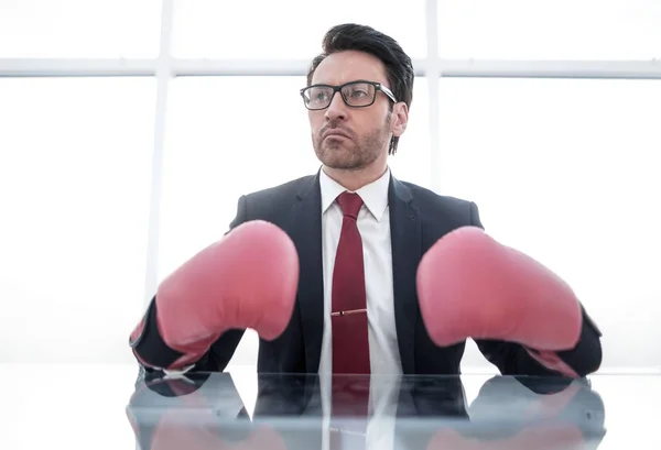 Confiado hombre de negocios en guantes de boxeo sentado en la oficina Des — Foto de Stock