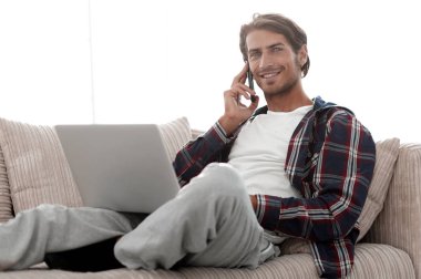 cep telefonu üzerinde konuşurken laptop ile ciddi genç adam