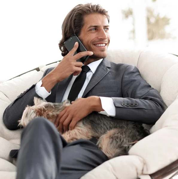 successful businessman holds his dog and pet and talks on the smartphone