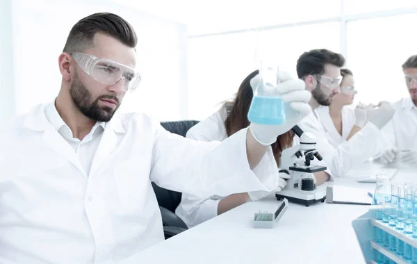 Биохимик с фляжкой Петри сидит за столом — стоковое фото