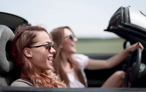 Dos chicas de moda viajan en un coche descapotable . — Foto de Stock