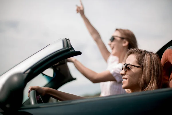 Stäng up.two unga kvinnor reser i en cabriolet bil — Stockfoto