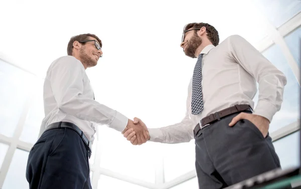 Inferior view.handshake socios de negocios de pie en la oficina —  Fotos de Stock