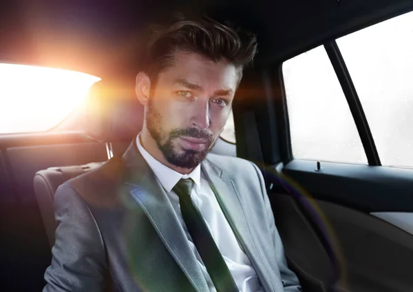 Hombre de traje sentado en el coche y leer mensajes en el teléfono inteligente — Foto de Stock