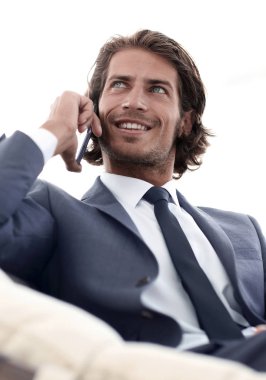 iş adamı rahat bir sandalyede otururken Smartphone'da konuşuyor.