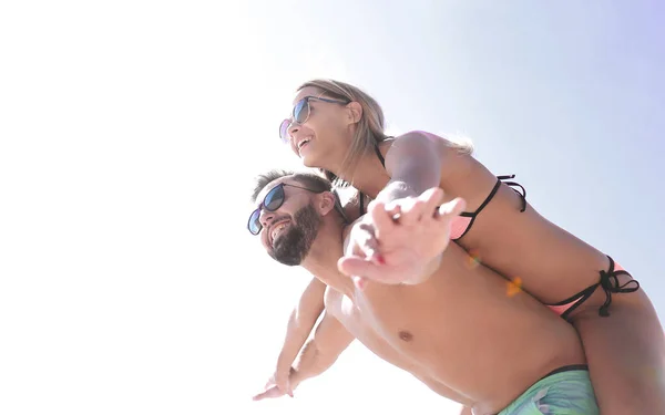 Uomo che trasporta donna a cavalluccio sulla spiaggia. — Foto Stock