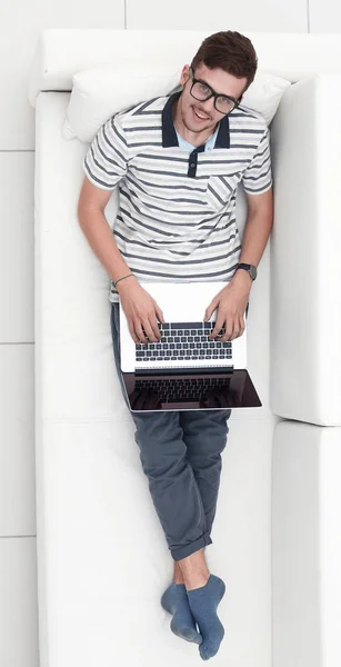 Современный человек работает на ноутбуке, сидя на диване — стоковое фото