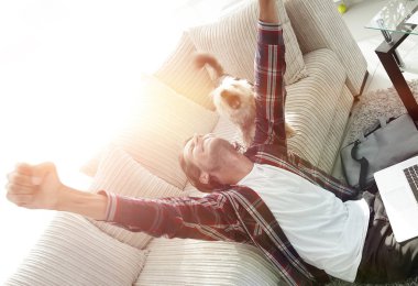 geniş bir oturma odasında otururken köpeğiyle mutlu adam