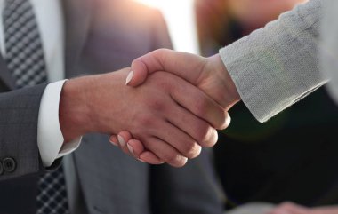 İş ortakları iş yerlerindeki iş eşyalarının üzerinden el sıkışıyor