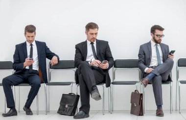 iş adamları cep telefonlarıyla office koridorda oturan