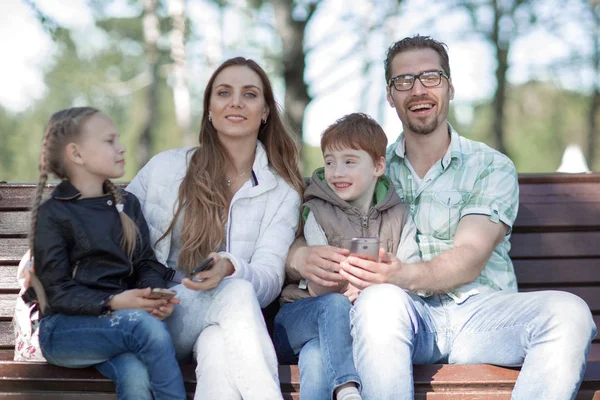 Porträtt av en lycklig familj som sitter på en parkbänk — Stockfoto