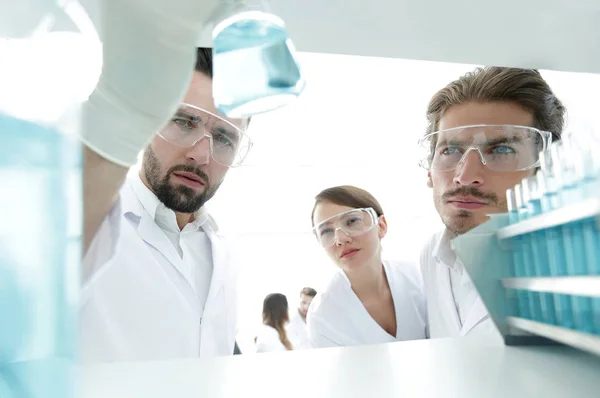 Primer plano. científico y asistente que estudia la solución en el tubo de vidrio — Foto de Stock