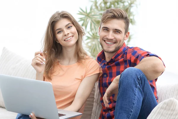 Jovem casal de estudantes com laptop sentado no sofá — Fotografia de Stock