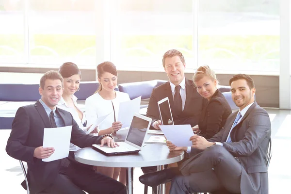 Grupo de empresarios con documentos sentados en una mesa en el vestíbulo del Banco . — Foto de Stock