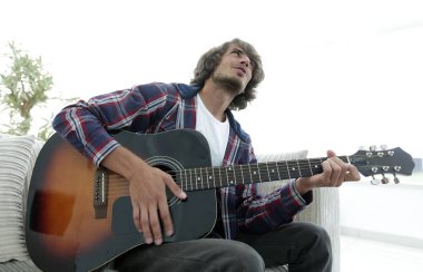 adam bir şarkı söyler ve kanepede oturan gitar çalar.