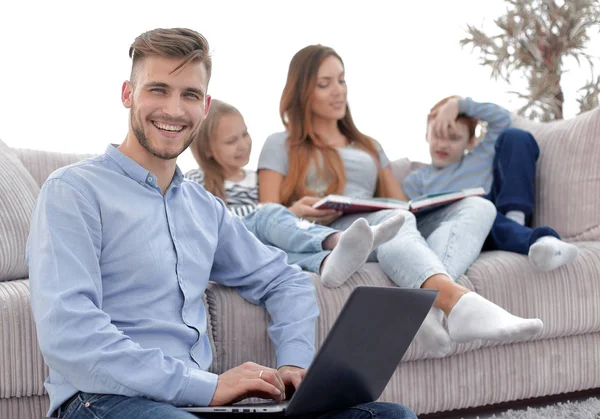 Uomo sorridente con computer portatile seduto nel suo salotto — Foto Stock