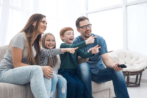 Lycklig familj sitter tittar på Tv i sitt hem — Stockfoto