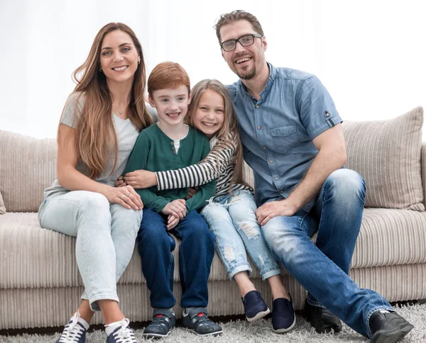 Familj med två barn som sitter i soffan i vardagsrummet — Stockfoto