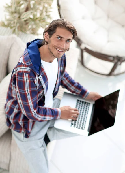Młody człowiek pracuje na laptopie i patrząc na kamery. od góry — Zdjęcie stockowe