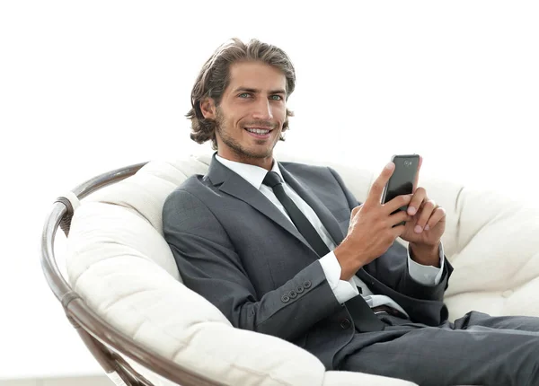 successful business man with a smartphone sitting in a comfortable chair