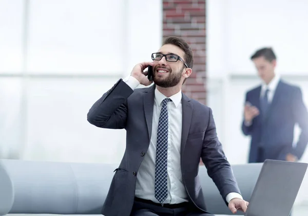 Confident young man talking on phone in office — Stock Photo, Image