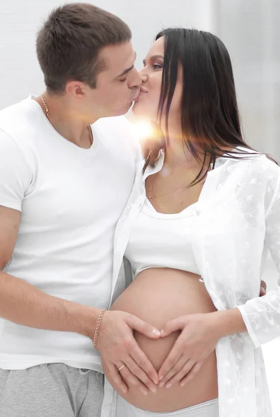 Husband and pregnant wife with folded hands in the shape of a heart on his tummy — Stock Photo, Image