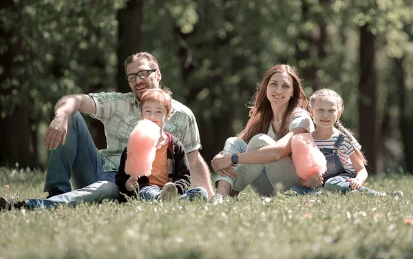 Gelukkige familie zitten op het gazon in de stad Park — Stockfoto