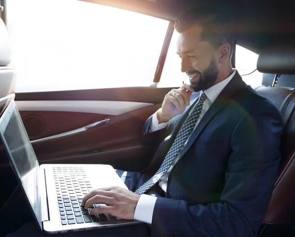 Uomo d'affari digitando testo sul computer portatile mentre seduto in auto — Foto Stock