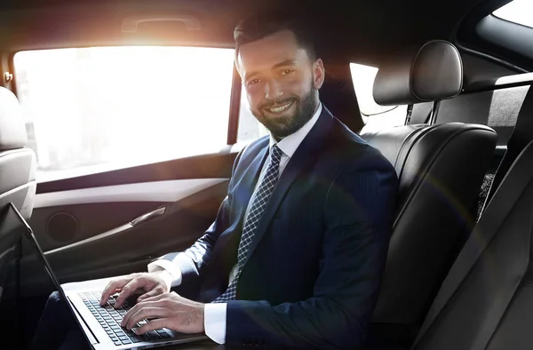 Uomo d'affari sorridente seduto sul sedile posteriore di una prestigiosa auto — Foto Stock