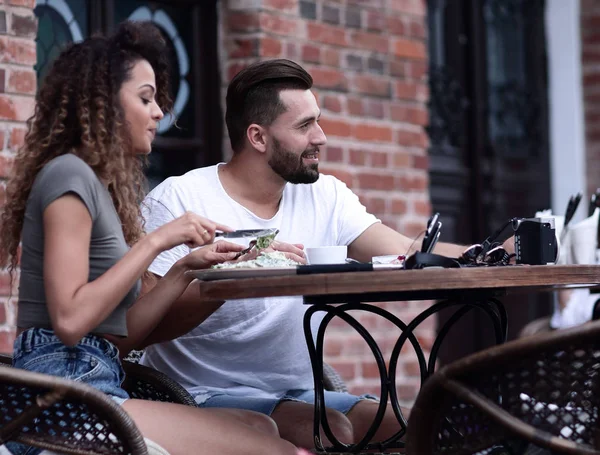 Jovem casal desfrutando de café em um café de rua e rindo — Fotografia de Stock