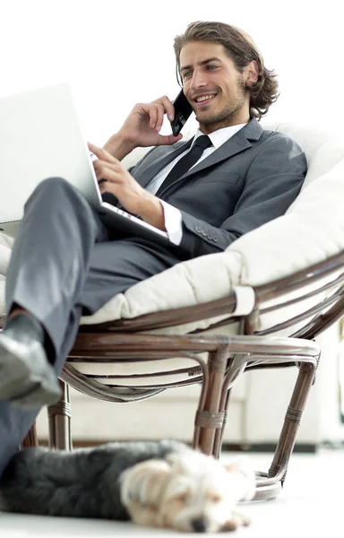 Empresário falando no smartphone sentado na cadeira em sua casa — Fotografia de Stock
