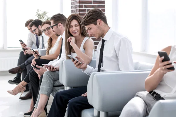 Gruppe von Mitarbeitern sitzt mit ihren Geräten auf dem Büroflur — Stockfoto