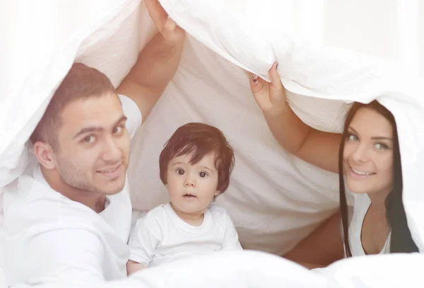 Famílias com crianças na cama sob um cobertor — Fotografia de Stock