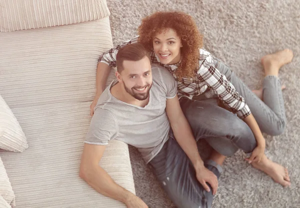 Young couple sitting on the carpet in the new living room — Stock Photo, Image