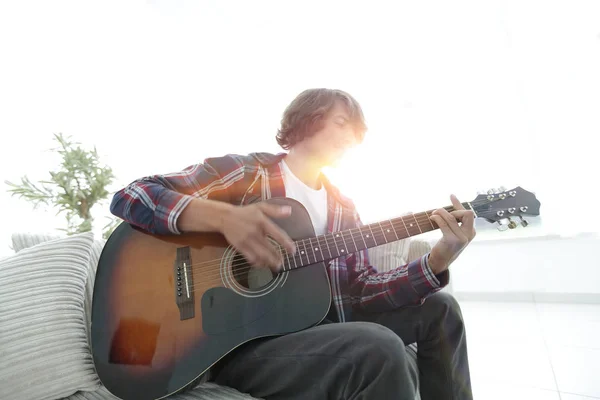 Guy sings a song and plays guitar sitting on the couch. — Stock Photo, Image