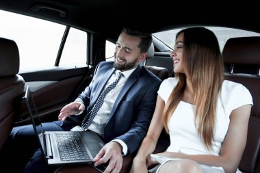 Genç iş adamları bir taksinin arka koltuğunda oturuyor.