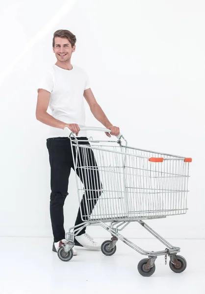 Mladý muž tlačí prázdný nákupní vozík — Stock fotografie