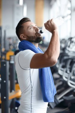 Trreadmill spor salonunda su şişe içki genç yetişkin adam.