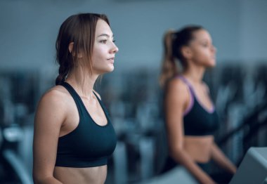 yan görünümü. Genç kadın fitness merkezinde bir koşu bandı üzerinde