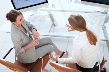 Üst kattan manzara. İş kadını, masaüstünde oturan bir meslektaşıyla konuşuyor.