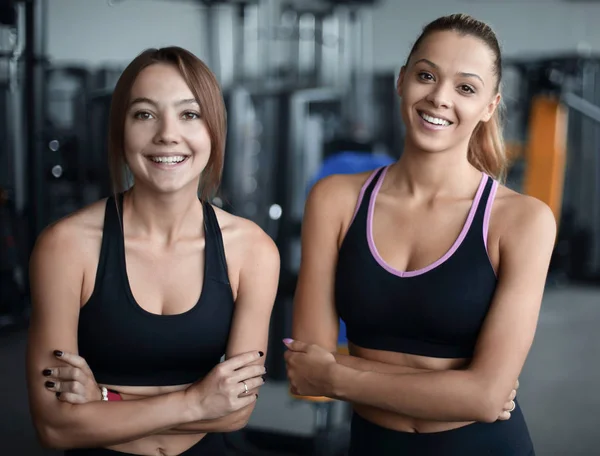 Dos mujeres jóvenes en el fondo del gimnasio — Foto de Stock