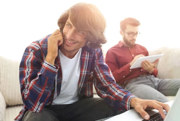 Two guys sitting on the couch, talking on the smartphone and communicating on the Internet. — Stock Photo, Image