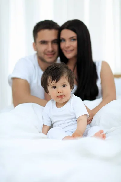Feliz pareja e hijo sentado en la cama —  Fotos de Stock