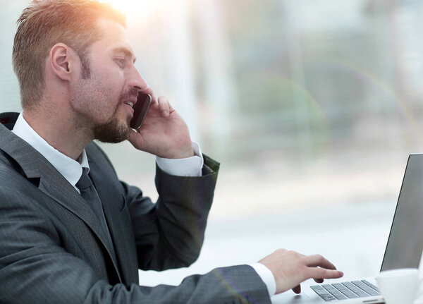 closeup.businessman working on laptop and talking on the phone