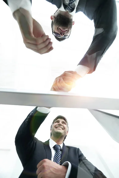 Vista desde abajo. Detrás del cristal. apretón de manos de socios comerciales — Foto de Stock