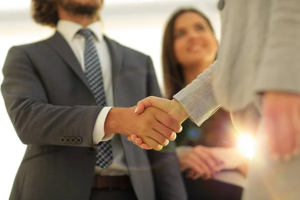 Businesspeople  shaking hands against room with large window loo — Stock Photo, Image