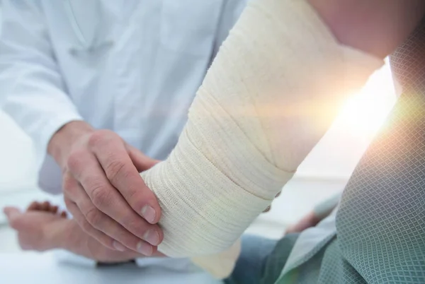 Orthopédiste appliquant un bandage sur les patients main dans la main en clinique — Photo