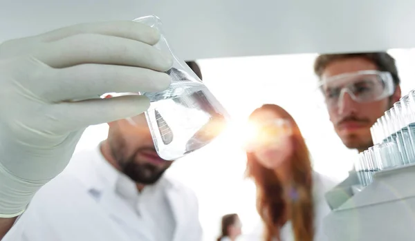 Closeup.a groep van wetenschappers bestuderen van de vloeistof in de glazen buis — Stockfoto