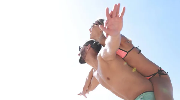 Uomo che trasporta donna a cavalluccio sulla spiaggia. — Foto Stock